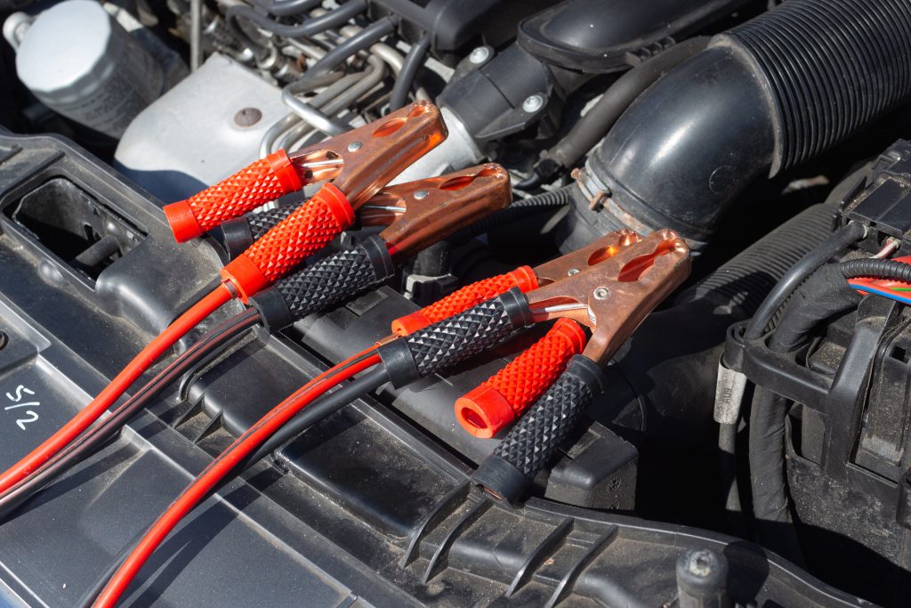 two red and two black jump leads placed on top of a car engine