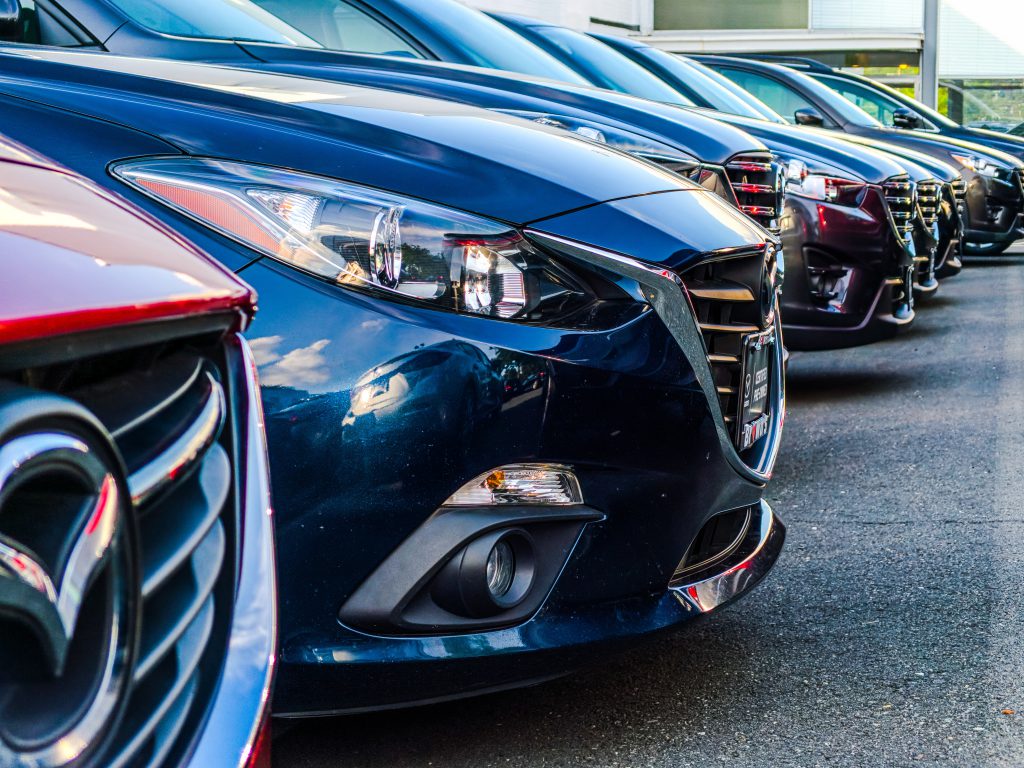 line of cars shown close up from the side where you can mostly just see bonnets