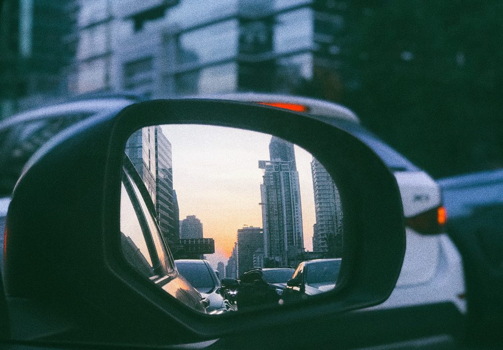 reflection of traffic and tall buildings in side mirror of a car