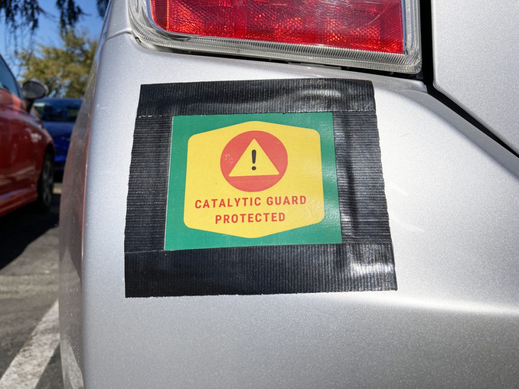 Catalytic Guard Protected sign on vehicle bumper. Catalytic converter