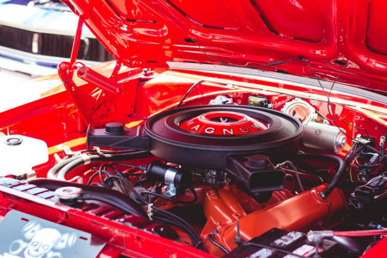 bonnet of a red car popped, showing engine with 'MAGNUM' showing on a central part
