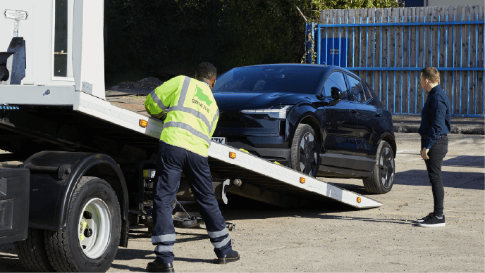 A black car is moved onto the back of a tow truck.