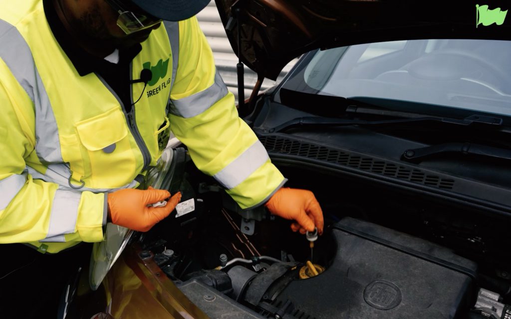 A Green Flag technician checks the engine oil using a dipstick.
