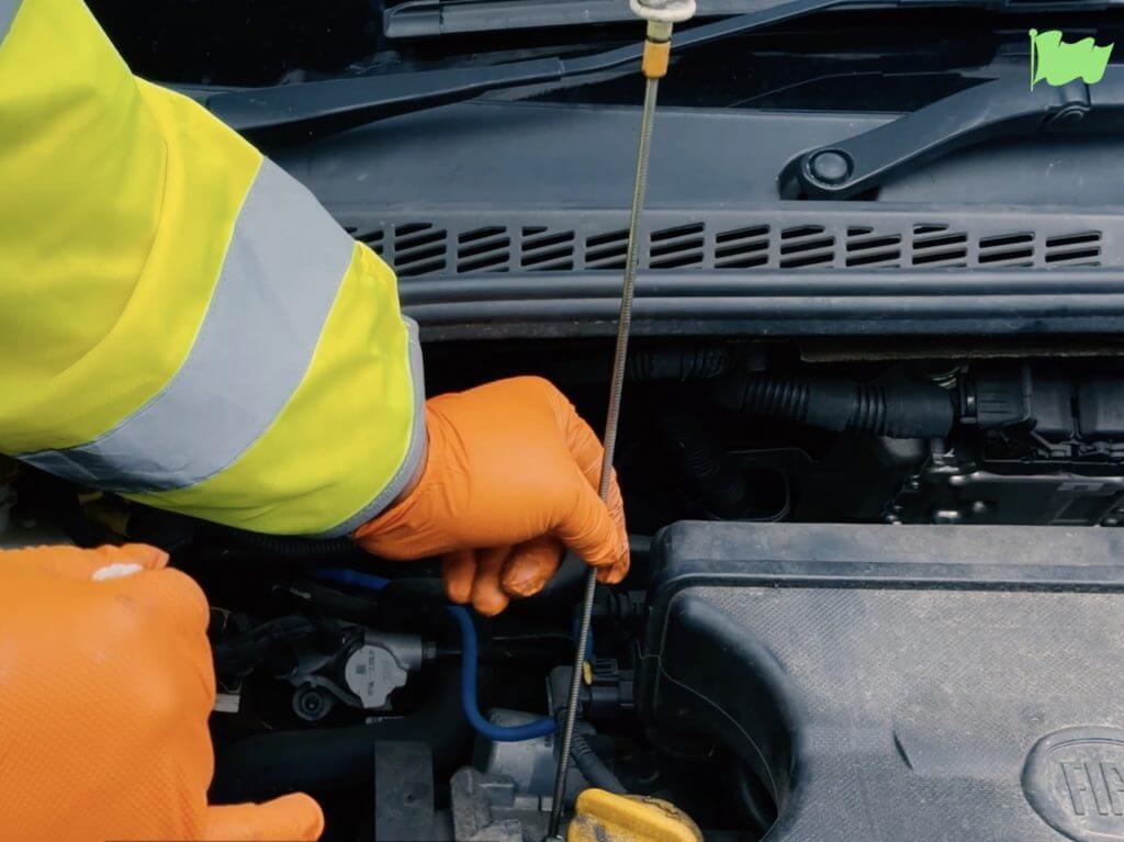 A Green Flag technician is seen holding the car's dipstick.