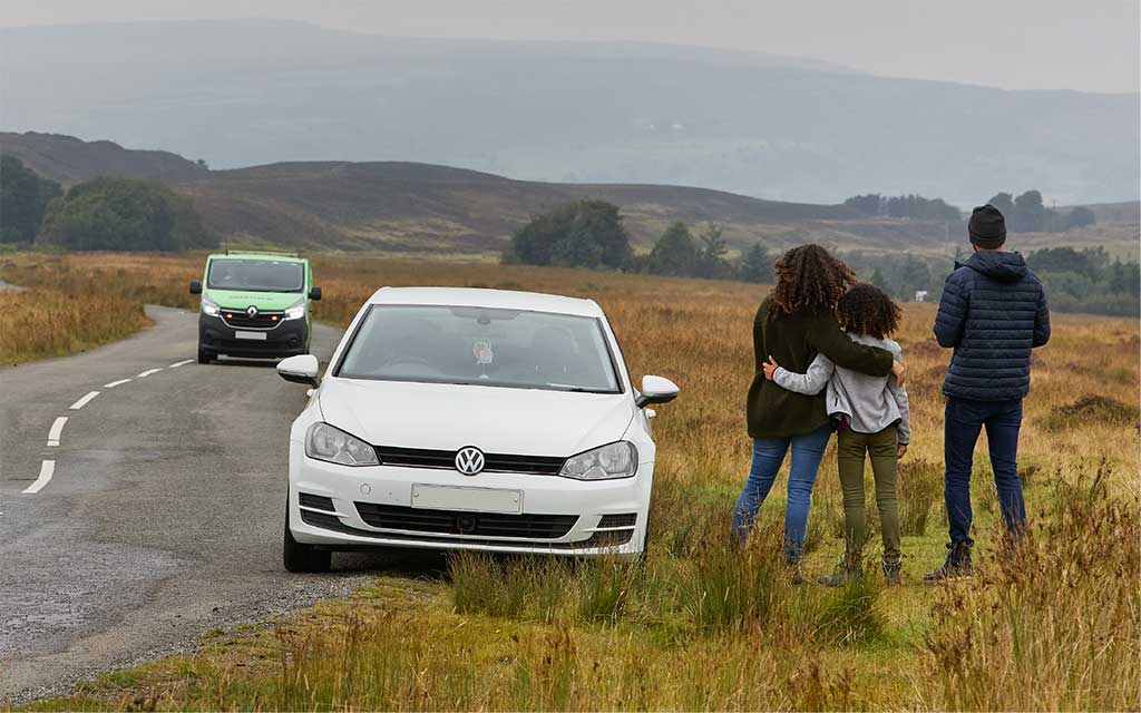 A family waits by their car for roadside recovery.