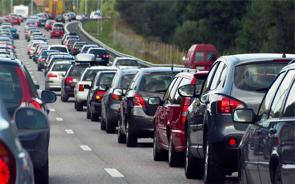 A motorway is jammed with cars, stretching out into the distance.