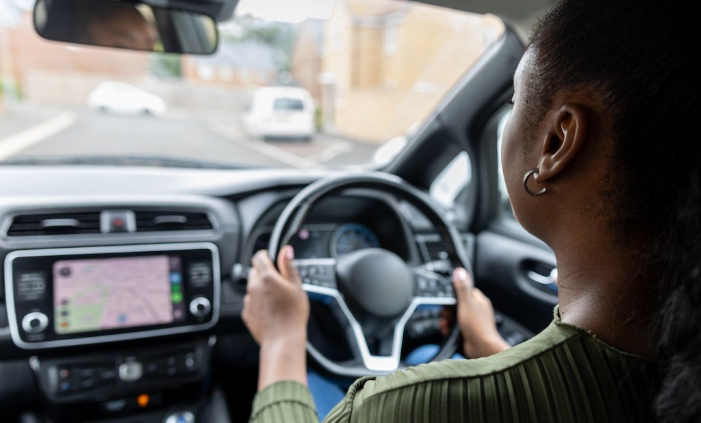 A lady is driving a car, following satnav directions.