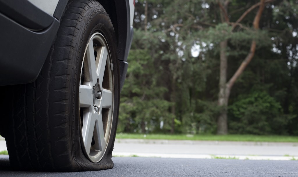 A car with a flat tyre is seen at the roadside.
