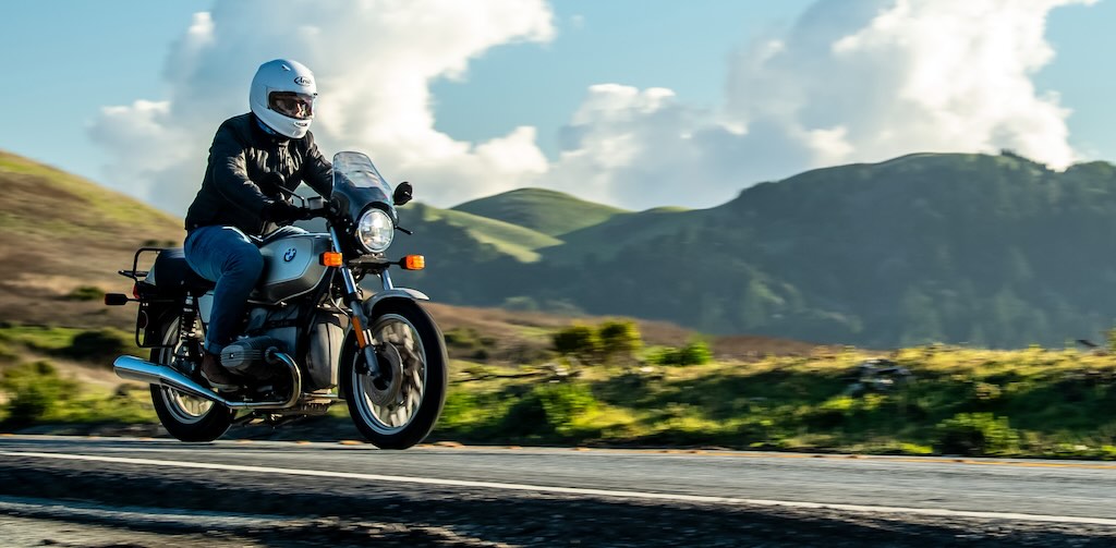 A black and silver motorbike is being driven through the countryside.